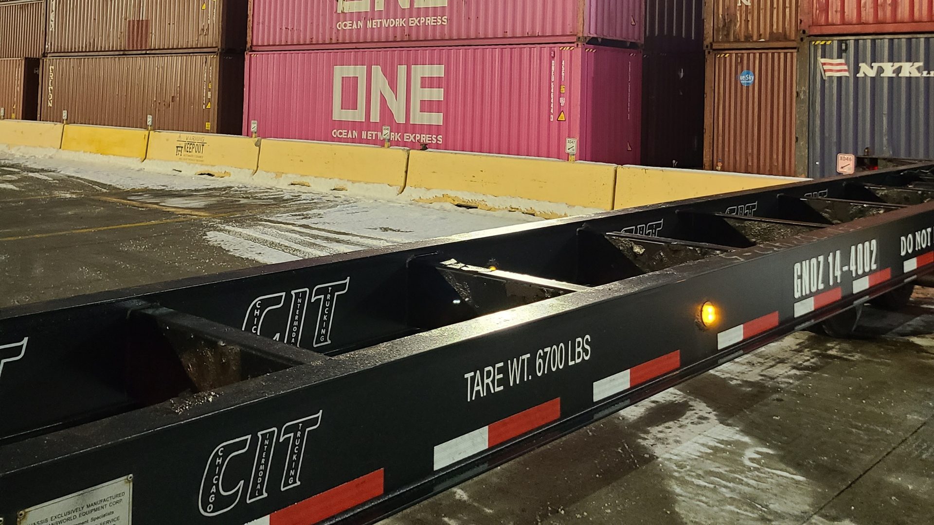 CIT gooseneck chassis loaded with a container at night in a Chicago rail yard